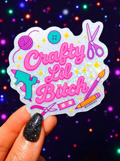 Funny Die-cut holographic craft sticker with pink “Crafty Lil Bitch” text, scissors and yarn.
