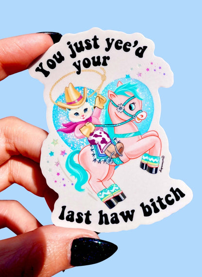 Funny White die-cut cowgirl cat sticker with cartoon rider and 'last haw bitch' text; hand-held