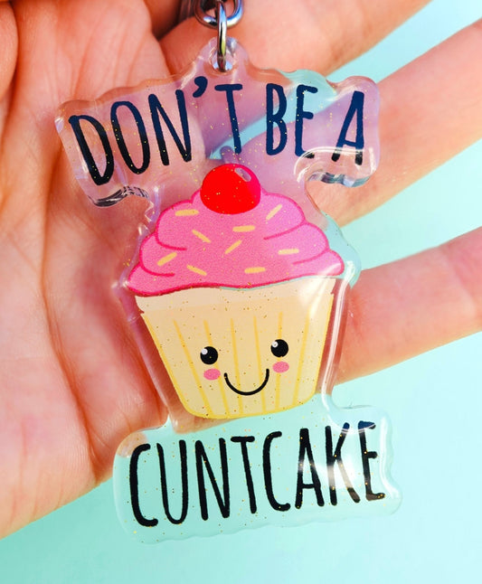 Funny Acrylic cupcake keychain with pink frosting and smile face, text DON’T BE A CUNTCAKE