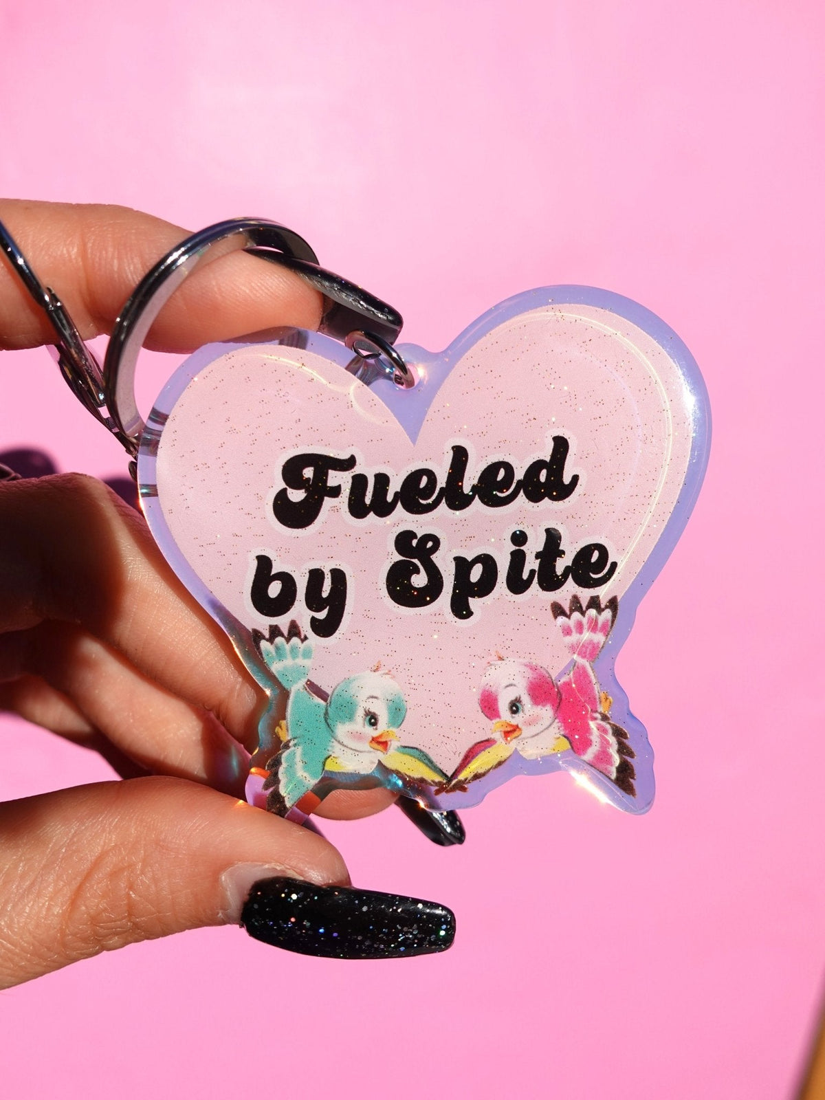 Funny Heart-shaped glitter keychain with “Fueled by Spite” text and cute character graphics
