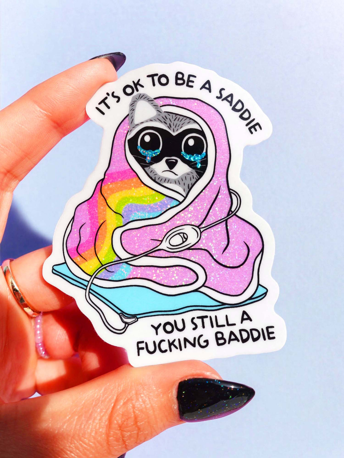 Funny Sticker featuring a sad raccoon with rainbow glow and text “You still a f***ing baddie”