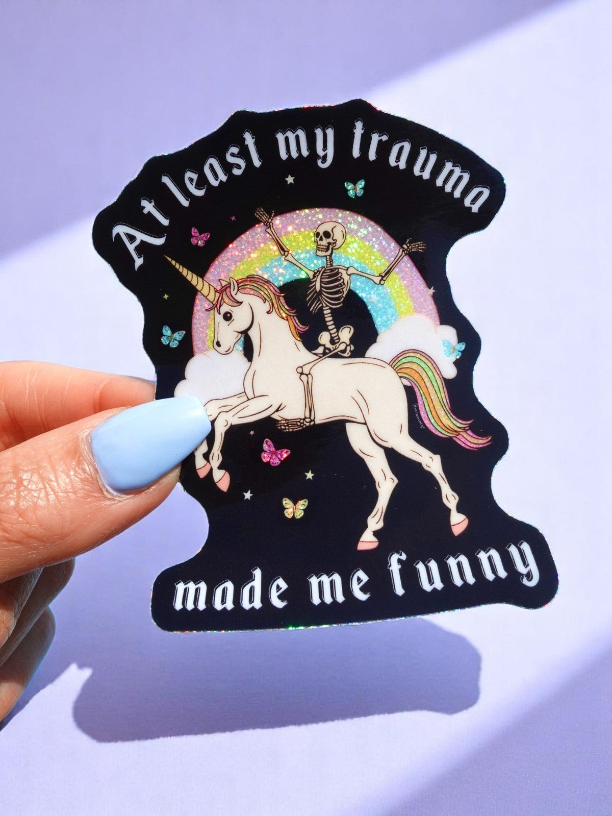 Black unicorn sticker with skeleton rider and text “At least my trauma made me funny”