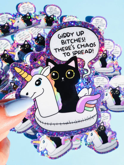 Funny Hand holding purple glitter cat and unicorn sticker with 'GIDDY UP' quote inside