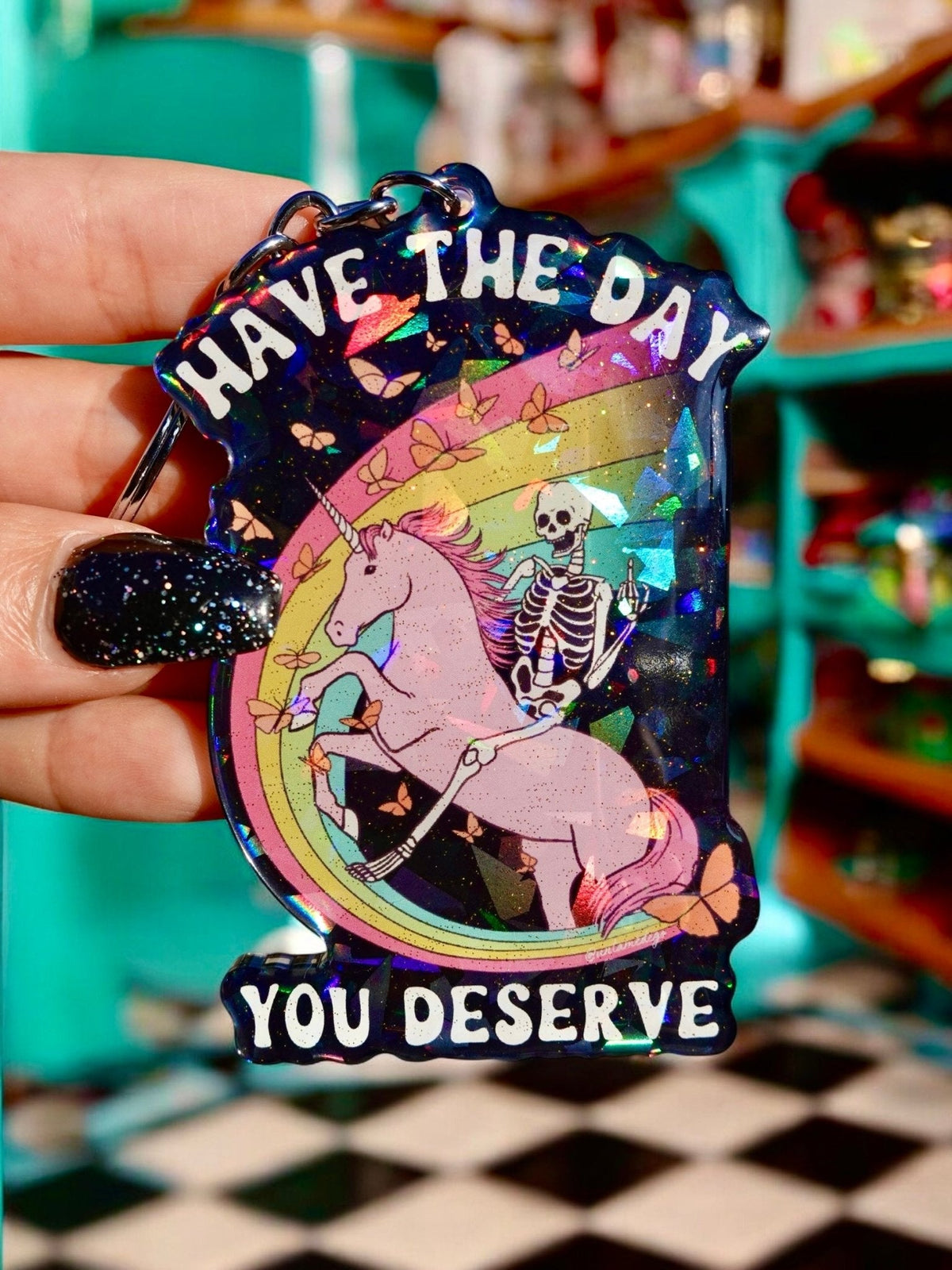 Funny Holographic keychain charm with unicorn skeleton graphic and Have the day you deserve text