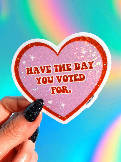 Funny Heart-shaped vinyl sticker with glitter purple heart, white outline, reads “Have the day you voted for.”