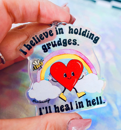Funny Heart keychain charm with red alien, rainbow, clouds, and quote text held in hand