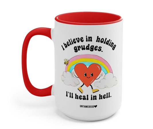Funny "I Believe In Holding Grudges I'll Heal In Hell" — White ceramic coffee mug with red handle and rim, graphic text and smiling character.