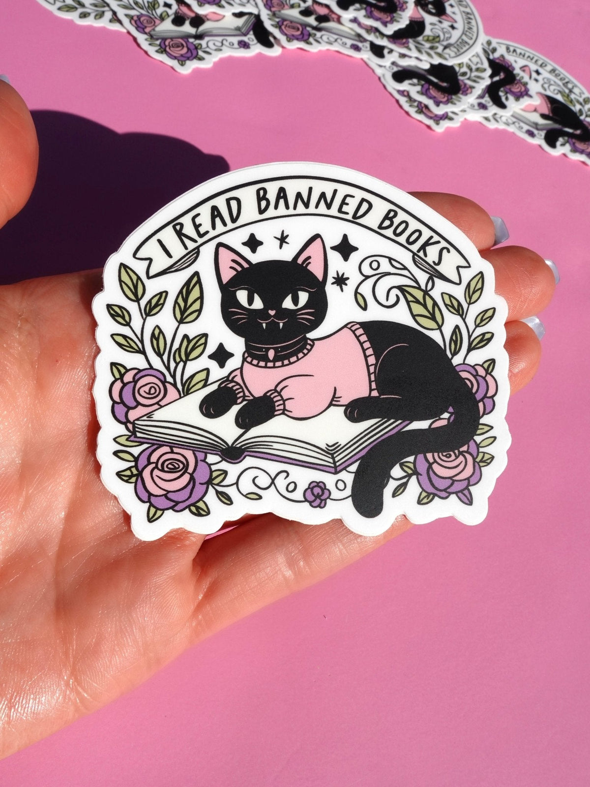 Funny Cat reading book sticker with floral roses, leaves, and circular 'I Read Banned Books' text