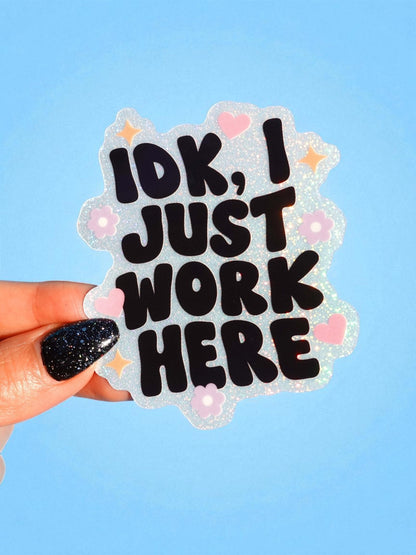 Funny Glitter work-slogan sticker with black text "IDK, I JUST WORK HERE" and pink hearts
