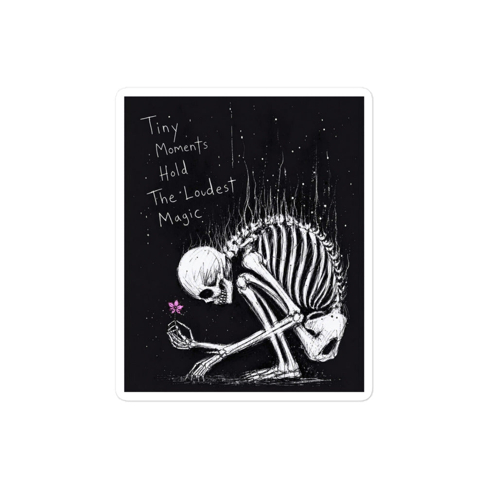 4 x 4 inch 'Tiny Moments' goth sticker featuring a kneeling skeleton holding a tiny pink flower on a black background, with the words "Tiny moments hold the loudest magic"