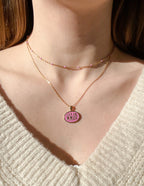 Elevated Faith Christian Jewelry featuring a layered gold necklace with a pink disk pendant
