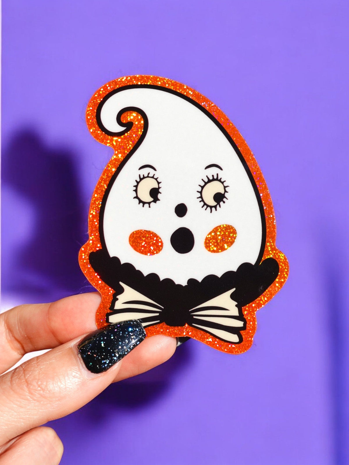 Funny Glitter retro ghost Halloween sticker with orange outline and black bowtie, held in hand