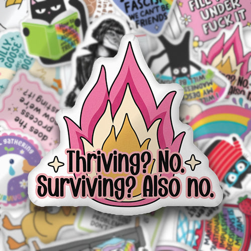 Flame-shaped throw pillow in pink and yellow with bold 'Thriving? No. Surviving?'