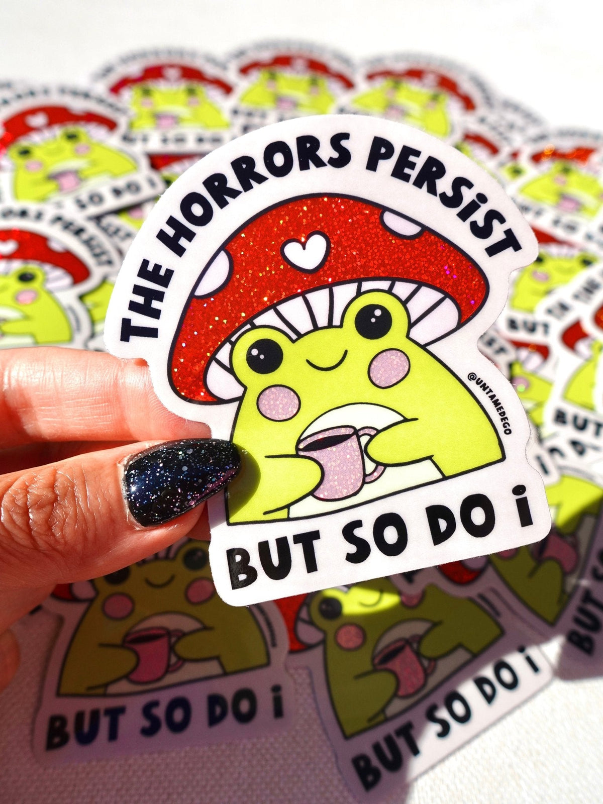 Funny Kawaii dinosaur sticker with red glitter band and text: 'THE HORRORS PERSIST' 'BUT SO DO I'