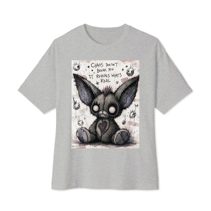 Athletic heather oversized boxy tee with the 'Chaos' goth graphic: a stitched gray big-eared creature with button eyes, with the words "Chaos doesn't break you, it reveals what's real"