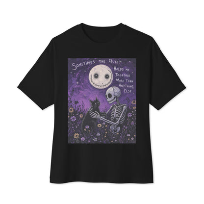 Black oversized boxy tee with the 'The Quiet Heals' goth graphic: a skeleton and a black cat in a purple flower field under a smiling moon, with the words "Sometimes the quiet holds me together more than anything else"