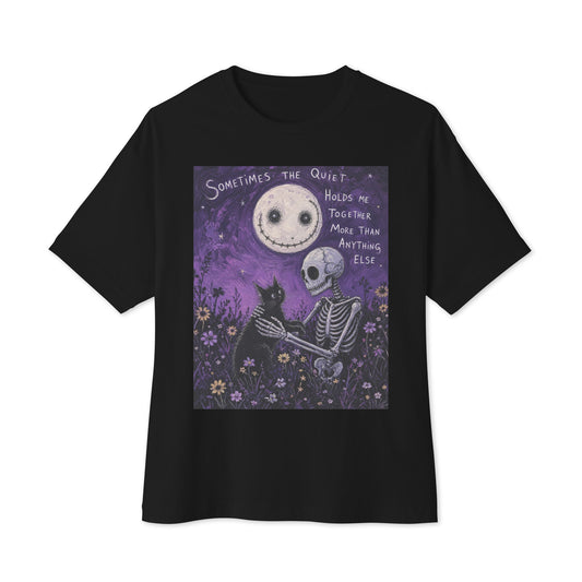 Black oversized boxy tee with the 'The Quiet Heals' goth graphic: a skeleton and a black cat in a purple flower field under a smiling moon, with the words "Sometimes the quiet holds me together more than anything else"
