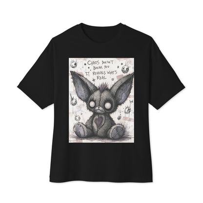 Black oversized boxy tee with the 'Chaos' goth graphic: a stitched gray big-eared creature with button eyes, with the words "Chaos doesn't break you, it reveals what's real"