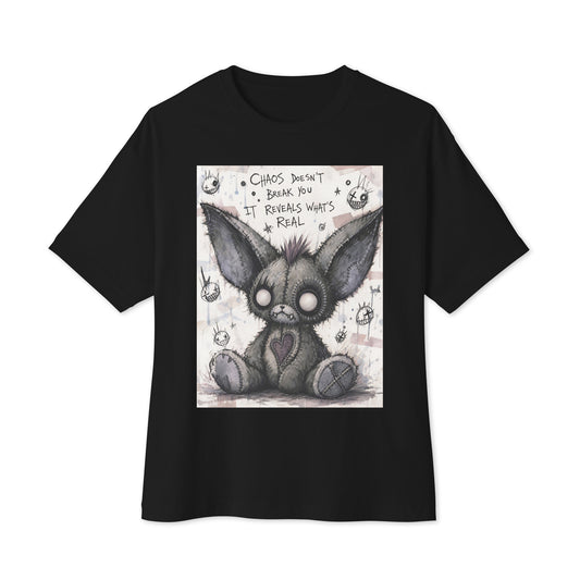 Black oversized boxy tee with the 'Chaos' goth graphic: a stitched gray big-eared creature with button eyes, with the words "Chaos doesn't break you, it reveals what's real"