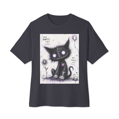 Dark grey oversized boxy tee with the 'Even Broken Things Can Bloom' goth graphic: a stitched black cat with glowing purple eyes beside a flower, with the words "Even broken things can bloom"