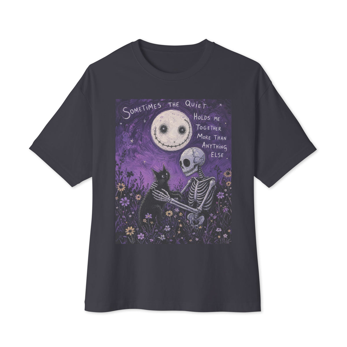 Dark grey oversized boxy tee with the 'The Quiet Heals' goth graphic: a skeleton and a black cat in a purple flower field under a smiling moon, with the words "Sometimes the quiet holds me together more than anything else"