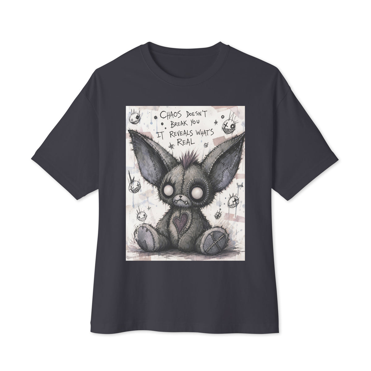 Dark grey oversized boxy tee with the 'Chaos' goth graphic: a stitched gray big-eared creature with button eyes, with the words "Chaos doesn't break you, it reveals what's real"