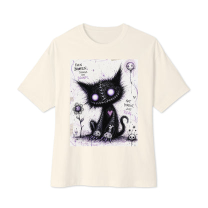 Natural oversized boxy tee with the 'Even Broken Things Can Bloom' goth graphic: a stitched black cat with glowing purple eyes beside a flower, with the words "Even broken things can bloom"