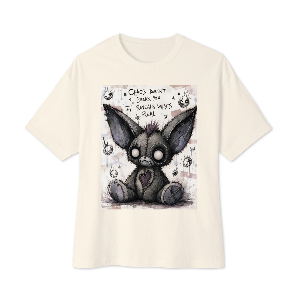 Natural oversized boxy tee with the 'Chaos' goth graphic: a stitched gray big-eared creature with button eyes, with the words "Chaos doesn't break you, it reveals what's real"