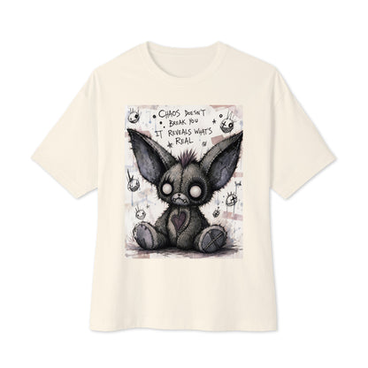 Natural oversized boxy tee with the 'Chaos' goth graphic: a stitched gray big-eared creature with button eyes, with the words "Chaos doesn't break you, it reveals what's real"
