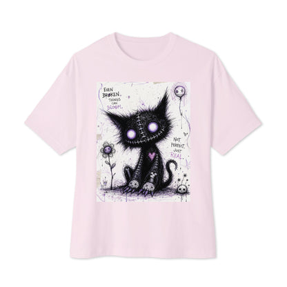 Soft pink oversized boxy tee with the 'Even Broken Things Can Bloom' goth graphic: a stitched black cat with glowing purple eyes beside a flower, with the words "Even broken things can bloom"
