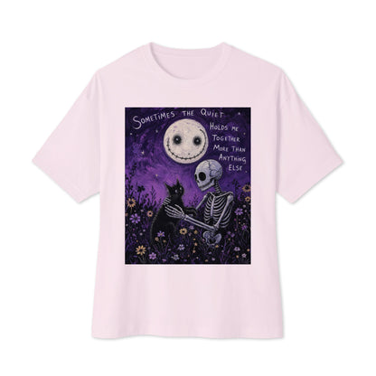 Soft pink oversized boxy tee with the 'The Quiet Heals' goth graphic: a skeleton and a black cat in a purple flower field under a smiling moon, with the words "Sometimes the quiet holds me together more than anything else"