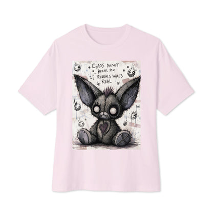 Soft pink oversized boxy tee with the 'Chaos' goth graphic: a stitched gray big-eared creature with button eyes, with the words "Chaos doesn't break you, it reveals what's real"