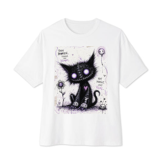 White oversized boxy tee with the 'Even Broken Things Can Bloom' goth graphic: a stitched black cat with glowing purple eyes beside a flower, with the words "Even broken things can bloom"