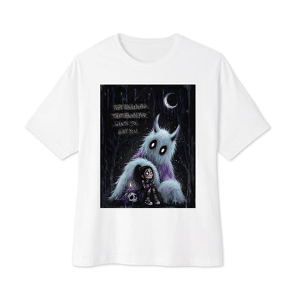 White oversized boxy tee with the 'The Haunted' goth graphic: a little goth girl holding a candle beside a fuzzy blue monster under a crescent moon, with the words "Not everything that haunts you wants to hurt you"