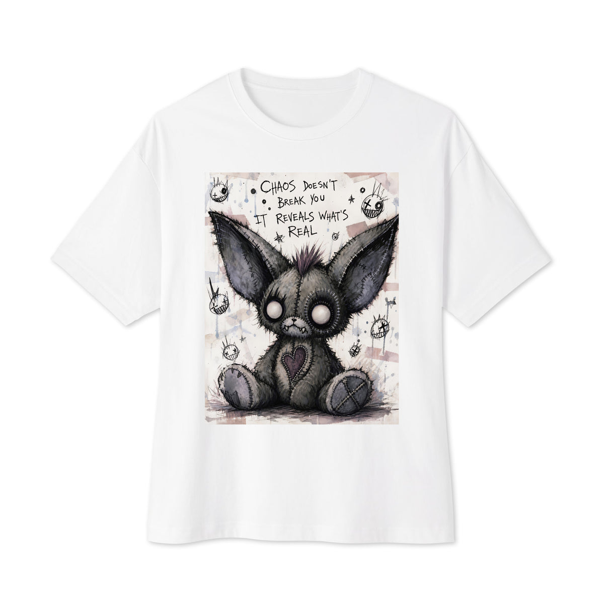White oversized boxy tee with the 'Chaos' goth graphic: a stitched gray big-eared creature with button eyes, with the words "Chaos doesn't break you, it reveals what's real"