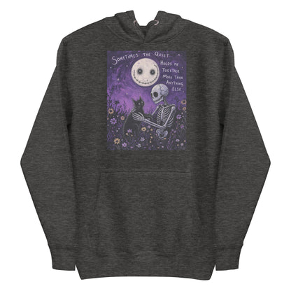 Charcoal heather pullover hoodie with the 'The Quiet Heals' goth graphic: a skeleton and a black cat in a purple flower field under a smiling moon, with the words "Sometimes the quiet holds me together more than anything else"