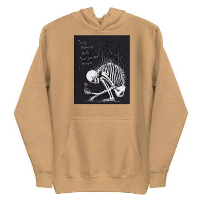 Khaki pullover hoodie with the 'Tiny Moments' goth graphic: a kneeling skeleton holding a tiny pink flower on a black background, with the words "Tiny moments hold the loudest magic"