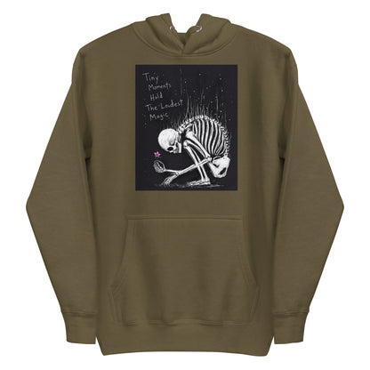 Military green pullover hoodie with the 'Tiny Moments' goth graphic: a kneeling skeleton holding a tiny pink flower on a black background, with the words "Tiny moments hold the loudest magic"