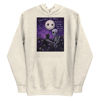 Oatmeal heather pullover hoodie with the 'The Quiet Heals' goth graphic: a skeleton and a black cat in a purple flower field under a smiling moon, with the words "Sometimes the quiet holds me together more than anything else"