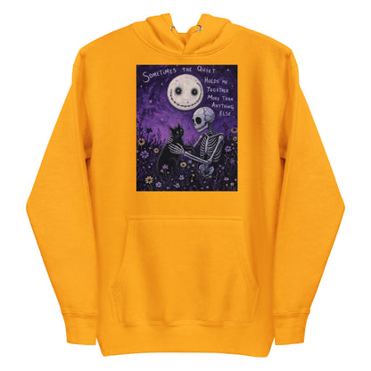 Gold pullover hoodie with the 'The Quiet Heals' goth graphic: a skeleton and a black cat in a purple flower field under a smiling moon, with the words "Sometimes the quiet holds me together more than anything else"