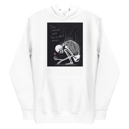 White pullover hoodie with the 'Tiny Moments' goth graphic: a kneeling skeleton holding a tiny pink flower on a black background, with the words "Tiny moments hold the loudest magic"