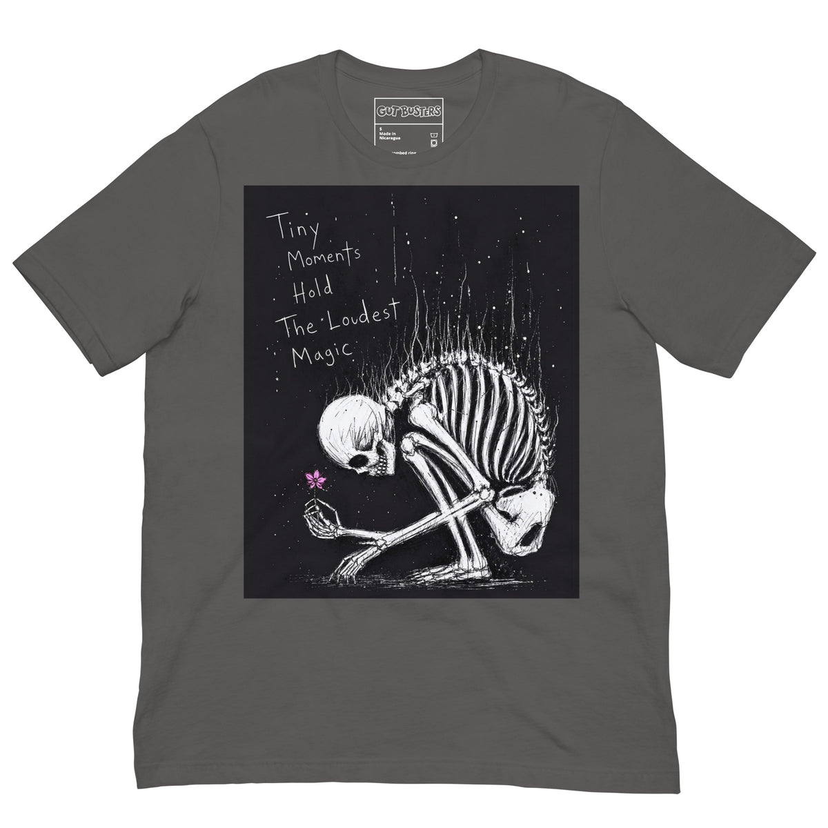 Asphalt unisex t-shirt with the 'Tiny Moments' goth graphic: a kneeling skeleton holding a tiny pink flower on a black background, with the words "Tiny moments hold the loudest magic"