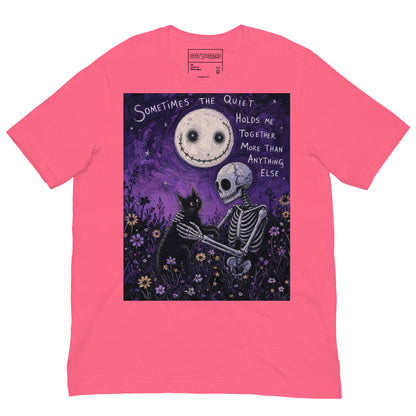 Pink unisex t-shirt with the 'The Quiet Heals' goth graphic: a skeleton and a black cat in a purple flower field under a smiling moon, with the words "Sometimes the quiet holds me together more than anything else"