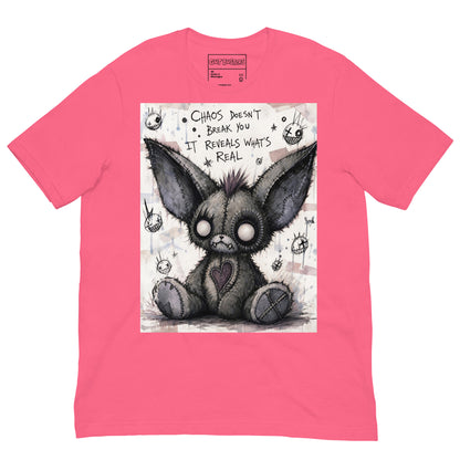 Pink unisex t-shirt with the 'Chaos' goth graphic: a stitched gray big-eared creature with button eyes, with the words "Chaos doesn't break you, it reveals what's real"