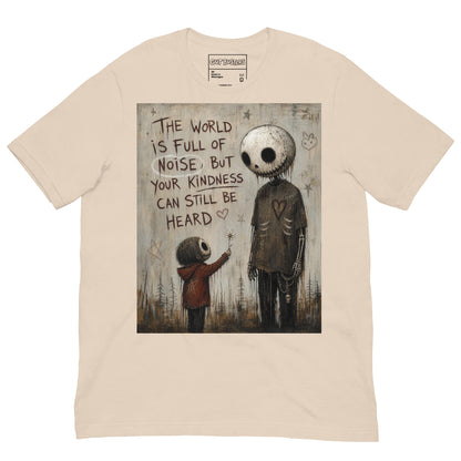 Soft cream unisex t-shirt with the 'Stay Kind' goth graphic: a tall skull-faced figure and a small child holding a flower, with the words "The world is full of noise, but your kindness can still be heard"