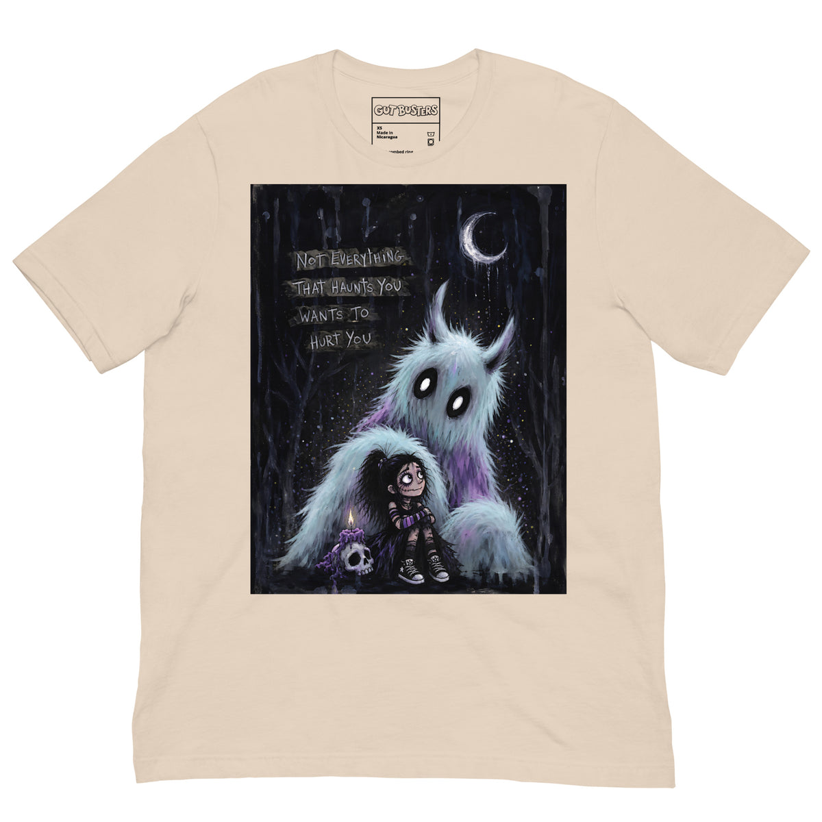 Soft cream unisex t-shirt with the 'The Haunted' goth graphic: a little goth girl holding a candle beside a fuzzy blue monster under a crescent moon, with the words "Not everything that haunts you wants to hurt you"