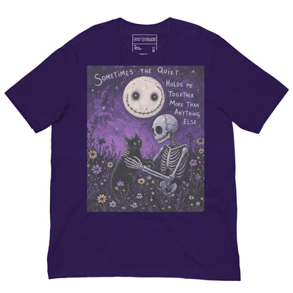 Purple unisex t-shirt with the 'The Quiet Heals' goth graphic: a skeleton and a black cat in a purple flower field under a smiling moon, with the words "Sometimes the quiet holds me together more than anything else"
