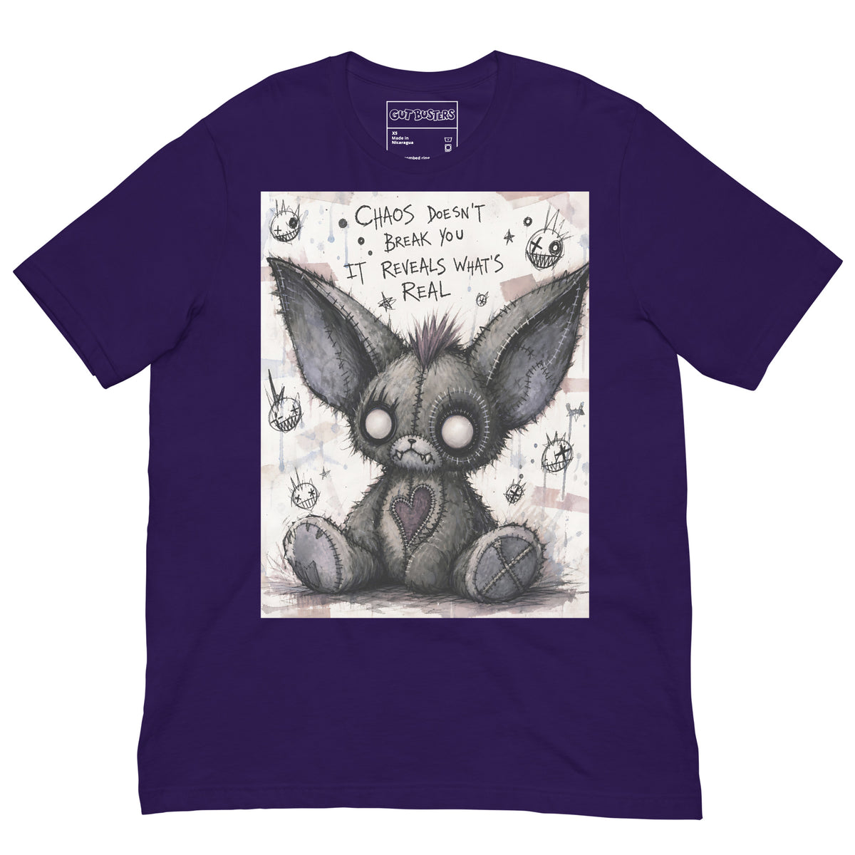 Purple unisex t-shirt with the 'Chaos' goth graphic: a stitched gray big-eared creature with button eyes, with the words "Chaos doesn't break you, it reveals what's real"