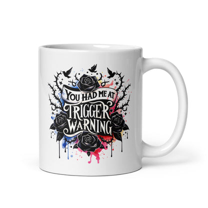 White glossy mug with centered 'Trigger warning' graphic and black rose artwork